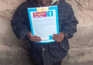 Na zdjęciu widać kenińskiego chłopca w mundurku szkolnym, który w rękach trzyma otrzymaną książkę.